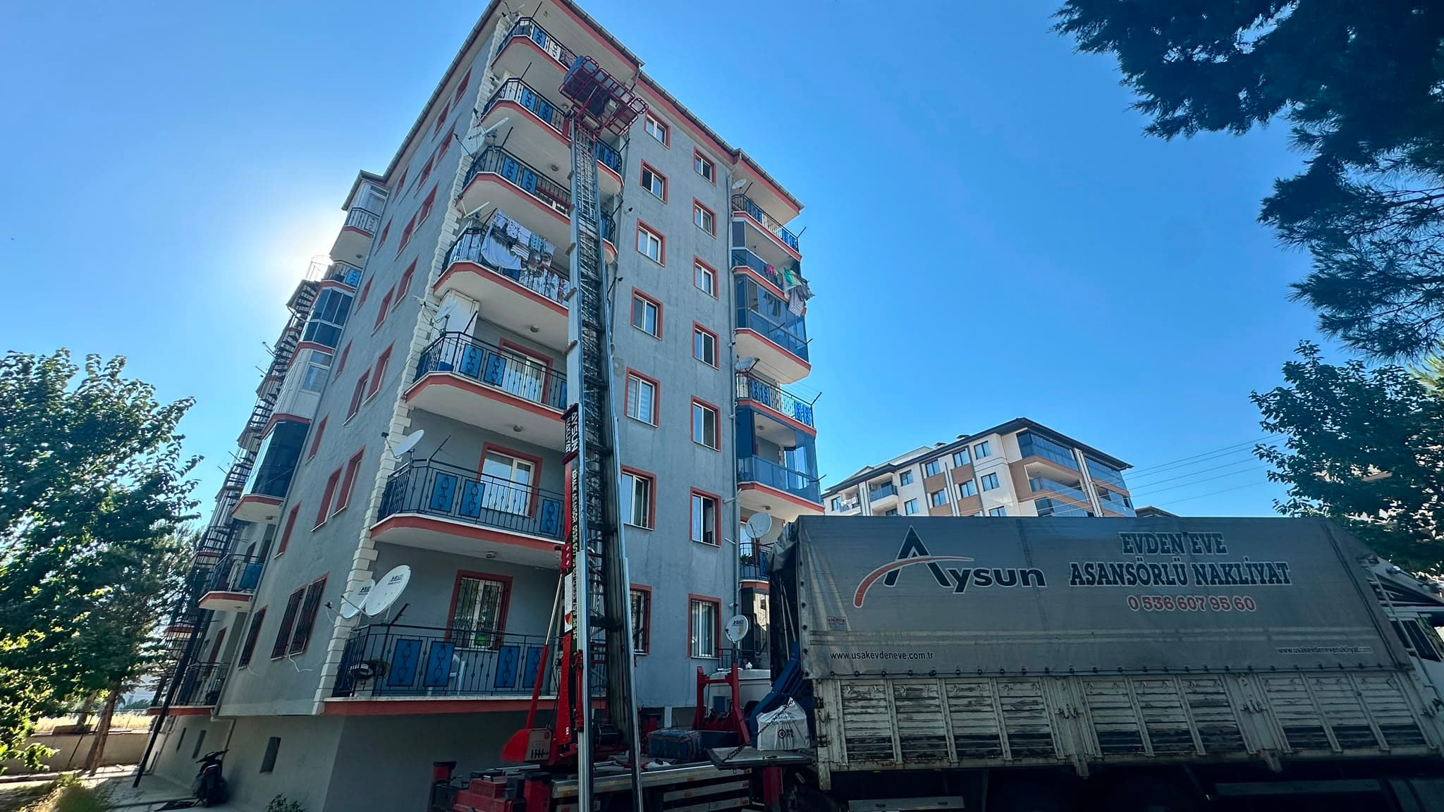 Uşak asansörlü nakliyat — bina önünde asansör ve taşıma kamyonu